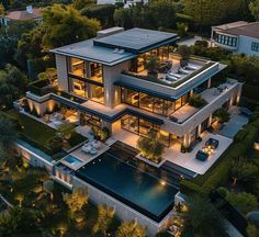 an aerial view of a modern house with pool in the foreground and lots of greenery