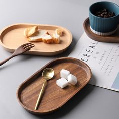 a wooden tray with marshmallows and bread on it next to a cup of coffee