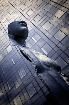 an artistic sculpture in the middle of a building's glass facade, looking up into the sky