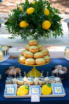 a table topped with lemons and pastries next to cupcakes on trays