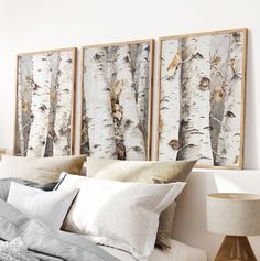 a bed topped with pillows next to two paintings