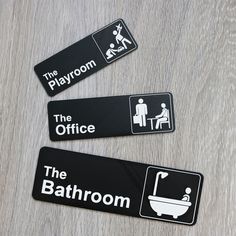 three black and white bathroom signs on a wooden floor with the words the playroom, the office, the bathroom