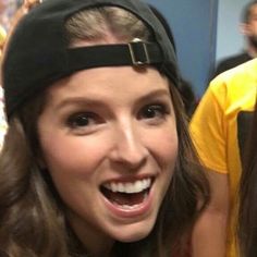 a woman wearing a black headband and smiling at the camera with other people in the background