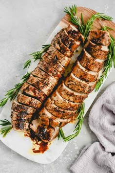 sliced pork on a cutting board with rosemary garnish