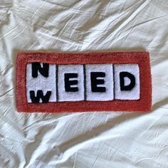 a red and white door mat with the words need spelled in black letters on it