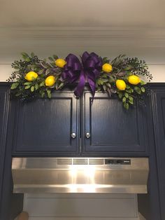 a kitchen decorated with yellow and purple flowers, greenery, and bow on the cabinets