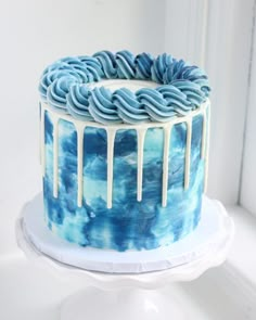 a blue and white cake with icing dripping from it