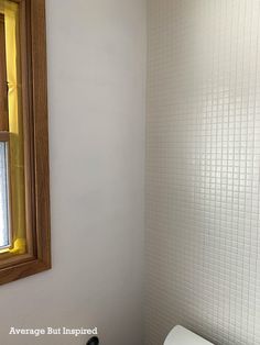 a white toilet sitting next to a bathroom sink under a wooden framed mirror on the wall