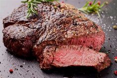 a piece of steak on a cutting board with spices and pepper sprinkles