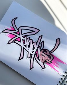 a white notebook with pink and black graffiti on it