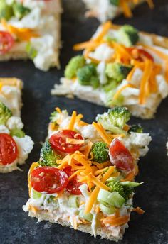 broccoli, tomatoes, cheese and other toppings are arranged on crackers