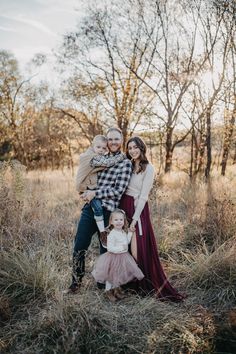 a family posing for a photo in an open field with tall grass and bare trees