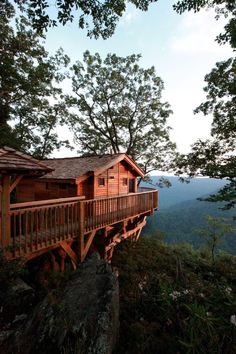 a wooden cabin on top of a mountain with a balcony and balconies in the trees