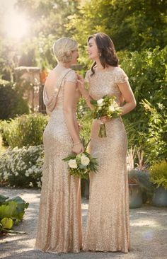 two women in gold dresses standing next to each other