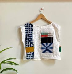 a white shirt hanging on a wooden hanger next to a potted green plant