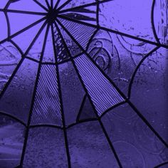 a close up of a glass window with water drops on it and an umbrella in the background