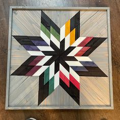 a multicolored star made out of wood sitting on top of a wooden floor