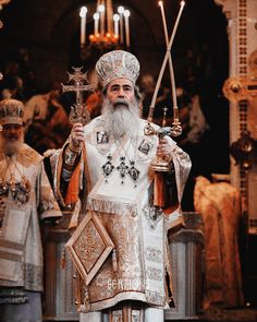 an old man with a long white beard wearing a crown and holding two candles in his hands