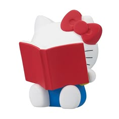 a hello kitty reading a book with a red bow on its head