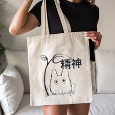 a woman holding a tote bag with an image of a rabbit on it and chinese writing