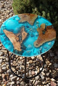 a blue glass plate sitting on top of a metal stand next to rocks and plants