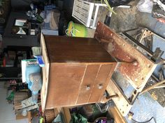 an old wooden cabinet sitting on top of a table in a room filled with junk