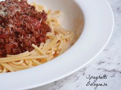 a white bowl filled with spaghetti and sauce