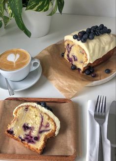 two slices of blueberry cake on brown paper next to a cup of cappuccino