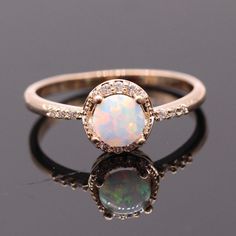 an opal and diamond ring on a reflective surface