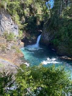 a waterfall in the middle of a river surrounded by trees