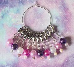 a bunch of beads hanging from a metal ring on a purple and white background with space for text