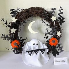 a halloween wreath with decorations on it and a white ghost face next to the wreath