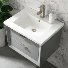 a white bathroom sink sitting next to a green plant