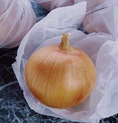 an onion sitting on top of some white paper wrapped in plastic wrappers next to another onion