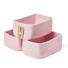 two pink storage baskets sitting on top of each other, one with a gold tag