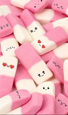 pink and white marshmallows with faces drawn on them are piled up together