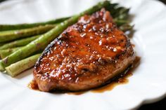 a piece of meat and asparagus on a white plate