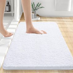 a person standing on top of a bath mat in a bathroom next to a plant