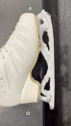 a pair of white sneakers with gold trims and snow on the bottom, sitting on top of a table