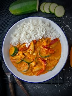 a white plate topped with rice and veggies next to cucumber slices