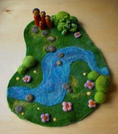 a small felt landscape with flowers and water