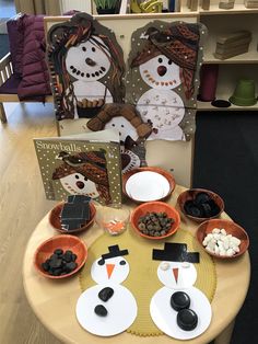 the table is set up with two snowmen and some bowls of food on it