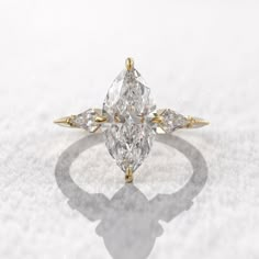 an engagement ring with three pear shaped diamonds on the front and side, in yellow gold