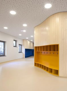 an empty room with yellow shelves on the wall