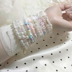 a woman's arm with bracelets and pearls on it