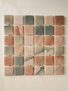 a white wall with some pink and grey tiles on it