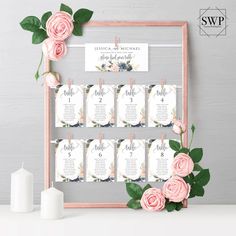 wedding seating chart with pink roses and greenery in front of a wooden frame on a table