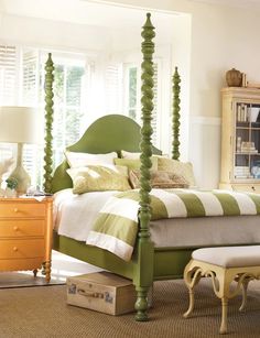 a green and white bedroom with four poster bed, dressers, mirror and chest of drawers