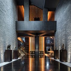 an empty hallway with stone walls and sculptures on the floor, in front of a staircase