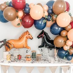 a party table with balloons and decorations on the wall, including a horse balloon sculpture